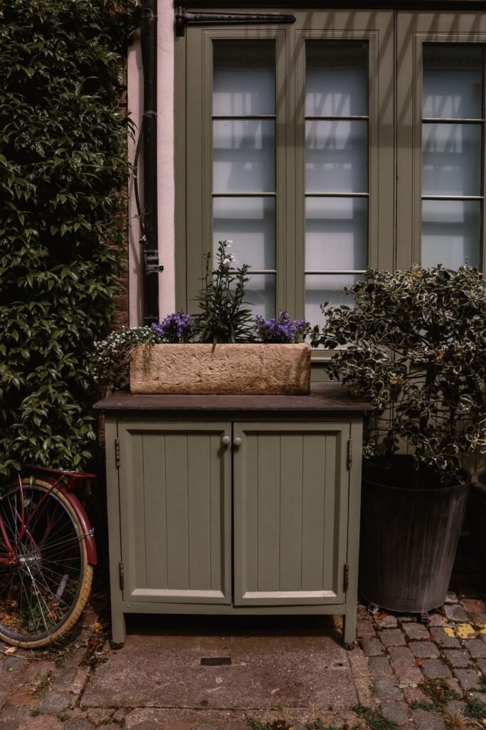 Groene houten kast met planten in een tuin, sfeer van een hoge houten tuinkast zoals bij hubo