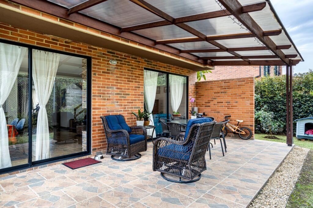 Overdekt terras met tuinmeubelen bij een bakstenen huis, plek voor een keter ontario box 870l
