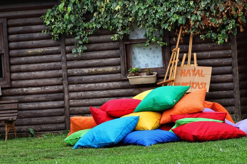 Kleurrijke tuinkussens op het gras naast een houten tuinhuis, op te bergen in een kussenbox van brico
