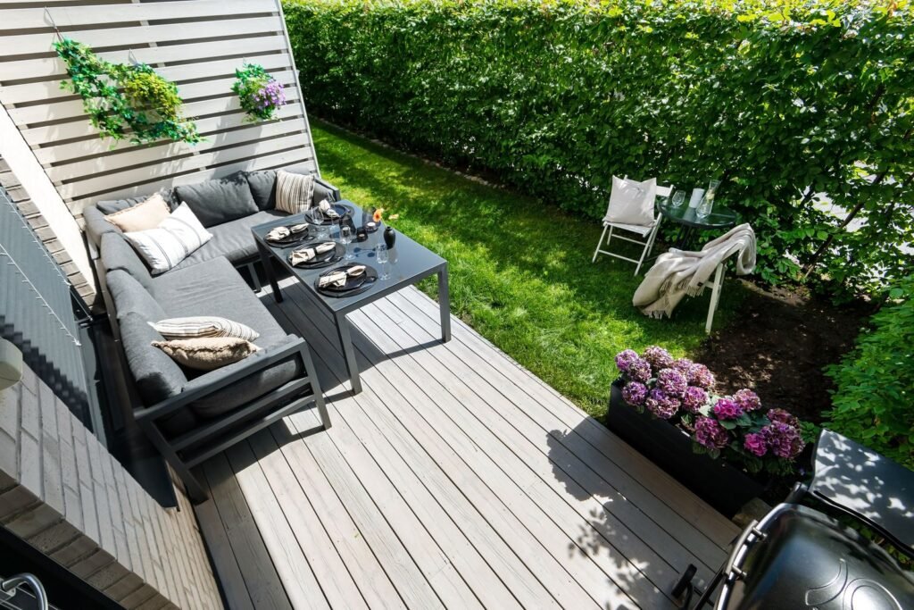 Grijze loungeset met kussens op een houten terras, perfect voor een kussenbox xxl waterdicht in aanbieding