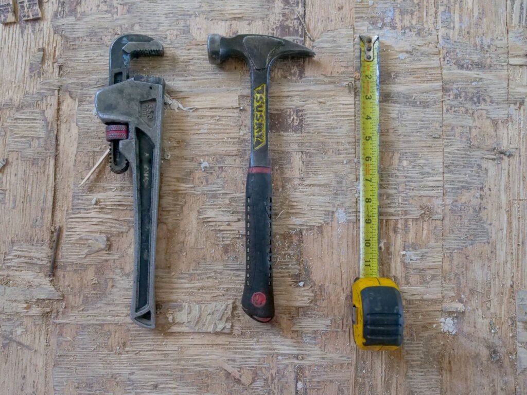 Gereedschap zoals hamer en moersleutel netjes tegen een wand, op te bergen in een metalen tuinkast antraciet