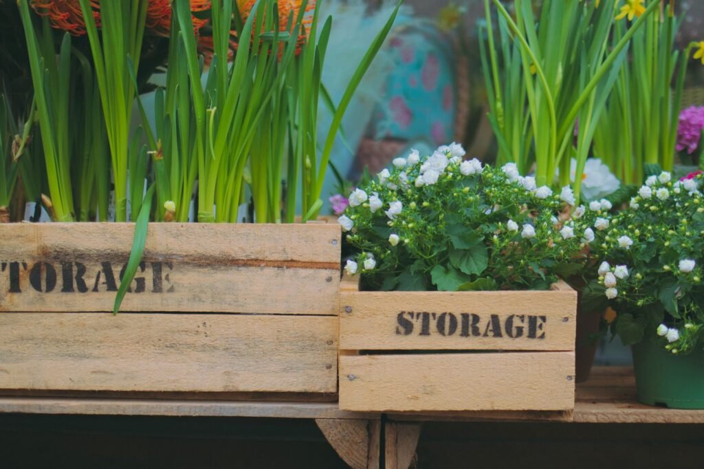Houten opbergkratten met planten op een terras, opbergideeën naast een opbergbox voor de tuin van action