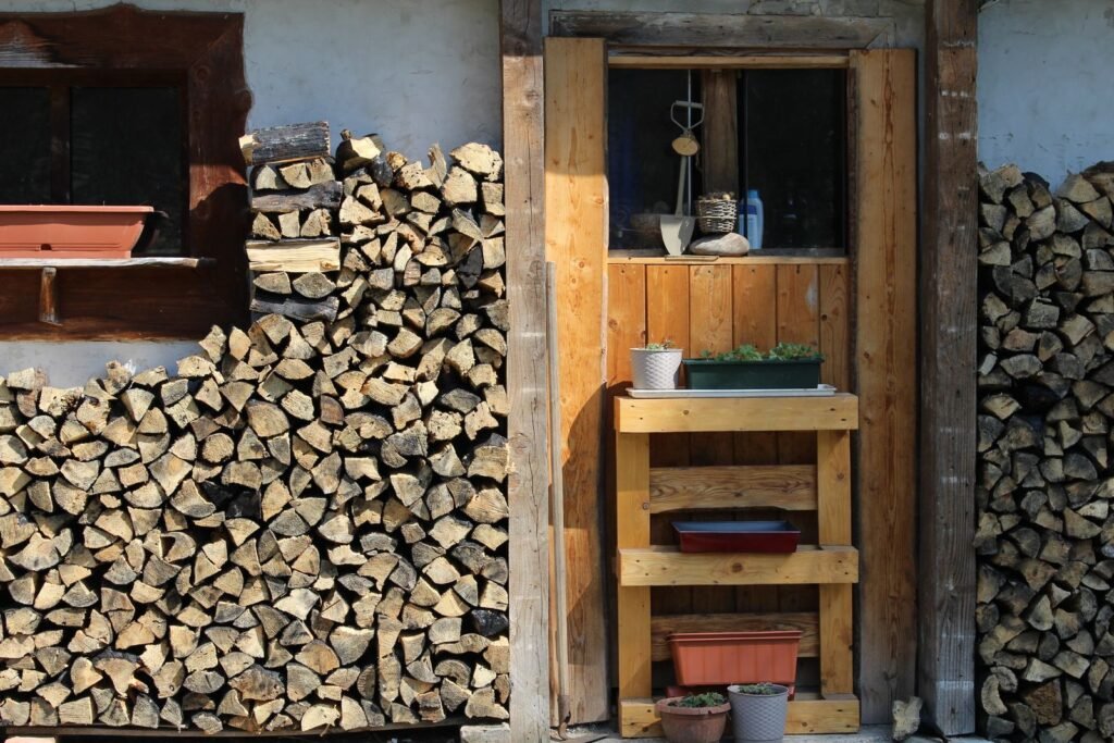 Houten opbergkast met brandhout tegen een gevel, stijl die past bij een tuinkist hout met zink dak