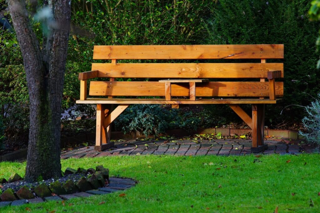 Houten tuinbank op het gras in een zonnige tuin, voorbeeld van een tuinkist houtbank buiten