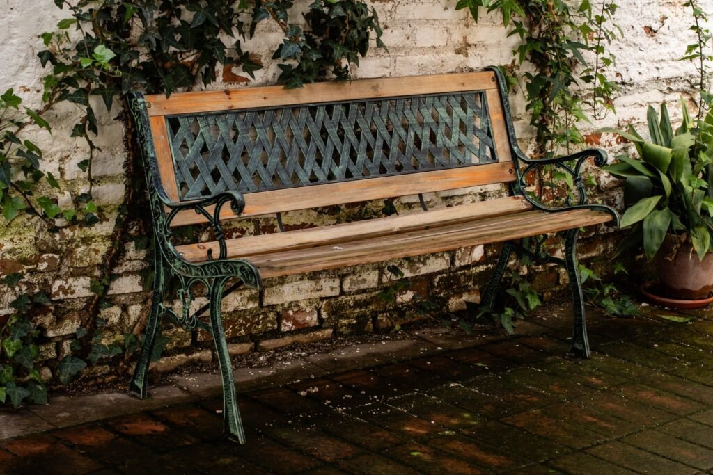 Houten tuinbank tussen de planten in een tuin, kussens die in een tuinkussen opbergtas van action passen