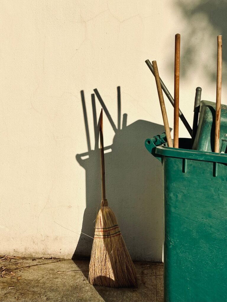 Harken en tuingereedschap rechtop in een bak tegen een muur, op te bergen in een waterdichte hoge tuinkast voor harken